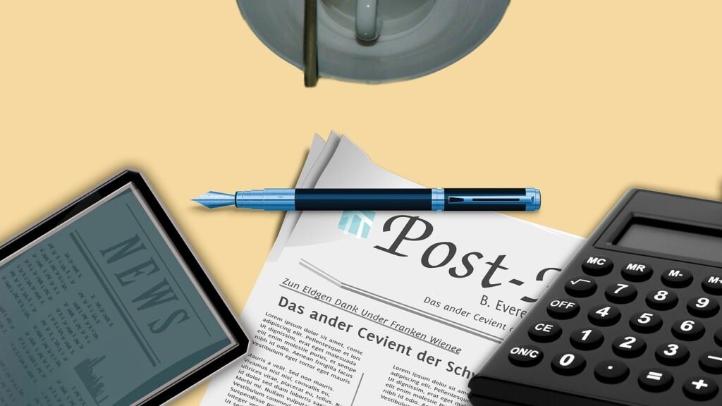 Una calculadora encima de un periódico y un boli
